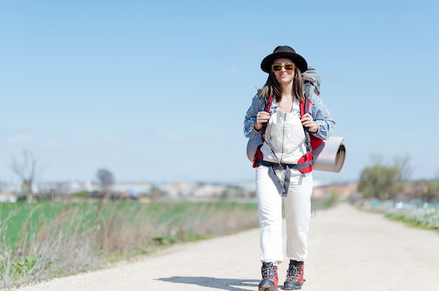 Mujer con mochila y colchoneta caminando