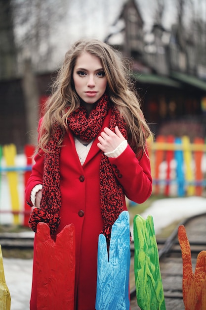 Mujer de moda en abrigo de invierno rojo y bufanda al aire libre