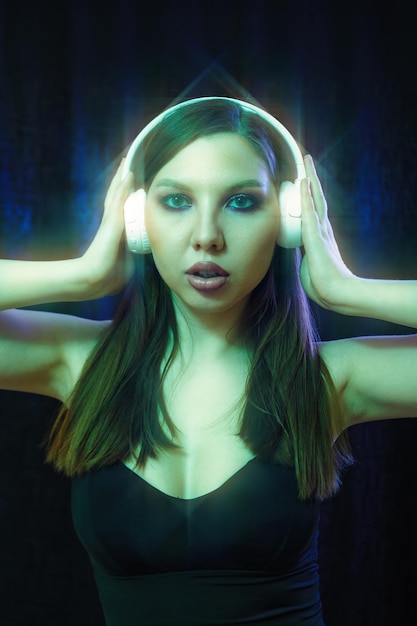 Mujer de moda con auriculares escuchando música sobre fondo de neón en el estudio