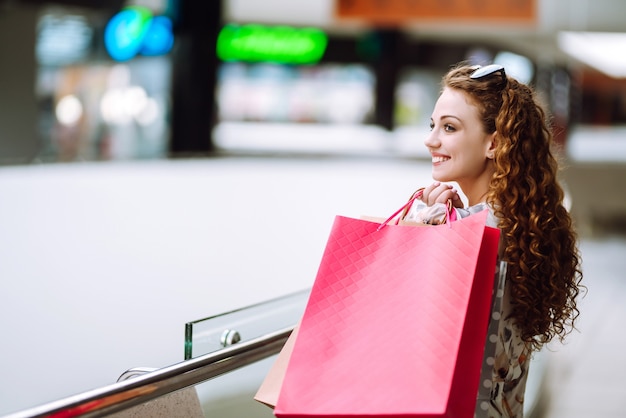 Mujer de moda con bolsos multicolores en el centro comercial. La alegría del consumo.