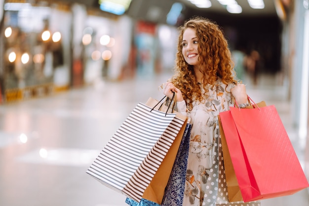 Mujer de moda con bolsos multicolores en el centro comercial. La alegría del consumo.