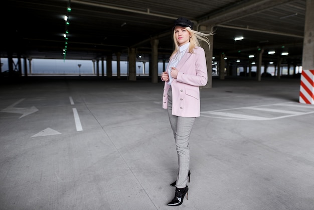 mujer de moda en una chaqueta posando en el estacionamiento