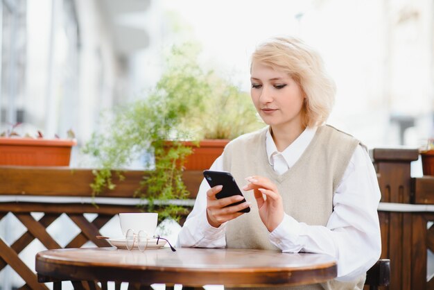 Mujer de moda hablando por teléfono en el café al aire libre