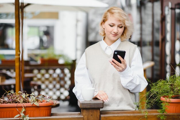 Mujer de moda hablando por teléfono en el café al aire libre