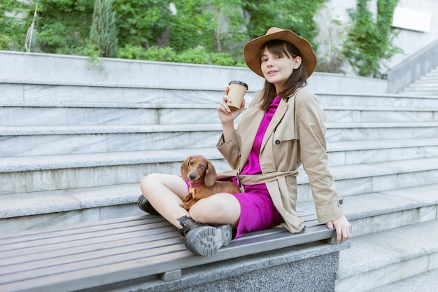 Mujer de moda joven y adorable cachorro dachshund en un parque de la ciudad. Ama y mascota