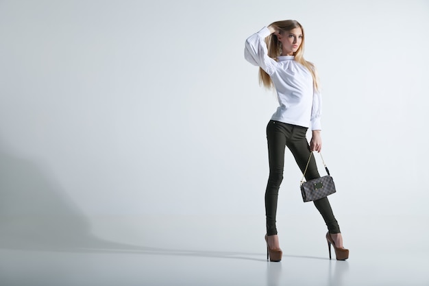 Mujer de moda joven casual de longitud completa con una bolsa en fondo claro