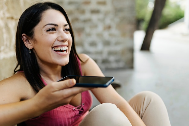 Mujer de moda joven enviando mensajes de voz o grabando sms de audio en el teléfono móvil