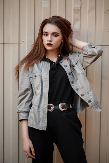 Mujer de moda joven modelo en polo negro y elegante chaqueta posando