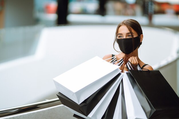 Mujer de moda con máscara médica protectora con bolsas de compras en el centro comercial.