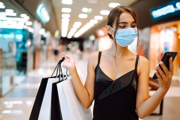 Mujer de moda con máscara médica protectora con bolsas de compras en el centro comercial.