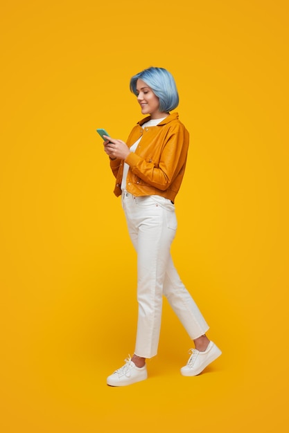 Mujer de moda navegando por teléfono inteligente en el estudio