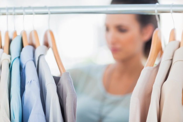 Mujer de moda que elige la ropa en el carril de la ropa