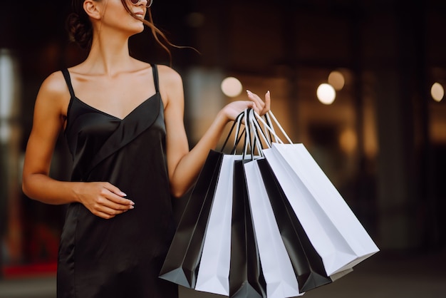 Mujer de moda vestida con un vestido negro con bolsas de la compra.