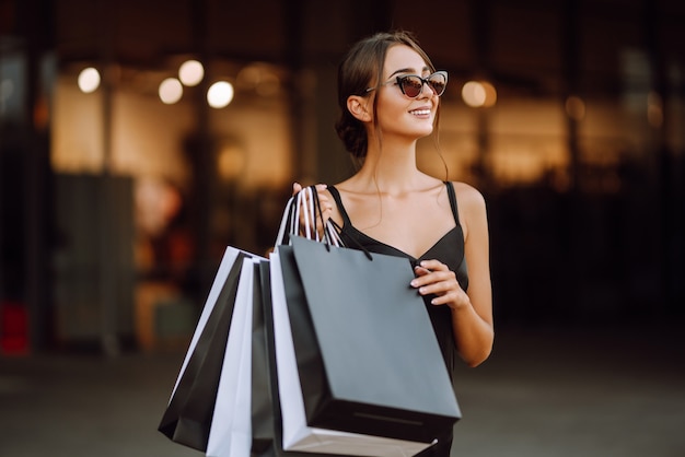 Mujer de moda vestida con un vestido negro con bolsas de la compra.