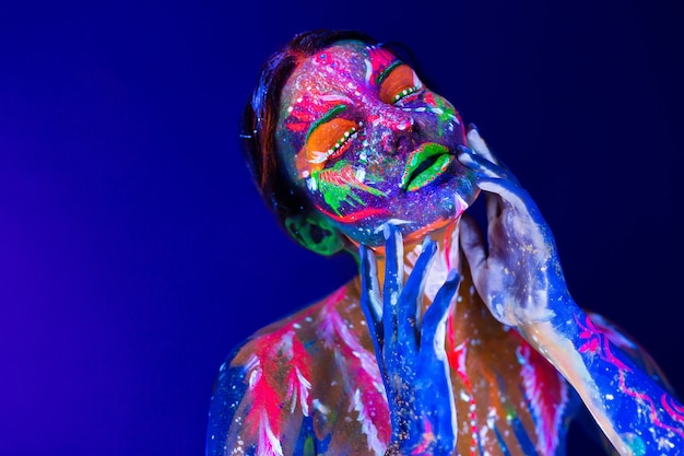 Mujer modelo de moda en luz de neón con maquillaje fluorescente.