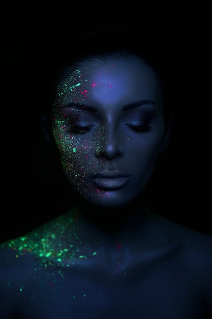 Mujer modelo de moda en maquillaje fluorescente brillante luz de neón, gota en la cara