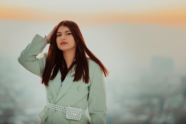 Una mujer moderna con una chaqueta verde posando afuera.