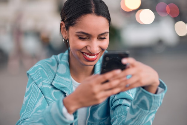 Mujer moderna, feliz y moderna enviando mensajes de texto en un teléfono navegando en las redes sociales o navegando por Internet Mujer soltera que parece segura y relajada sonriendo mientras lee un mensaje en una aplicación de citas en línea