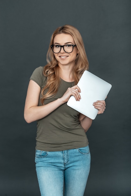 mujer moderna. Hermosa mujer joven en anteojos sonriendo y sosteniendo tableta digital