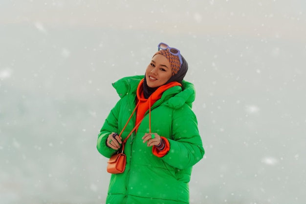 Mujer moderna en hijab con chaqueta verde posando en un día de invierno