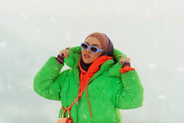 Mujer moderna en hijab con chaqueta verde posando en un día de invierno