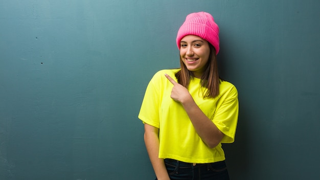 Mujer moderna joven que sonríe y que señala el lado