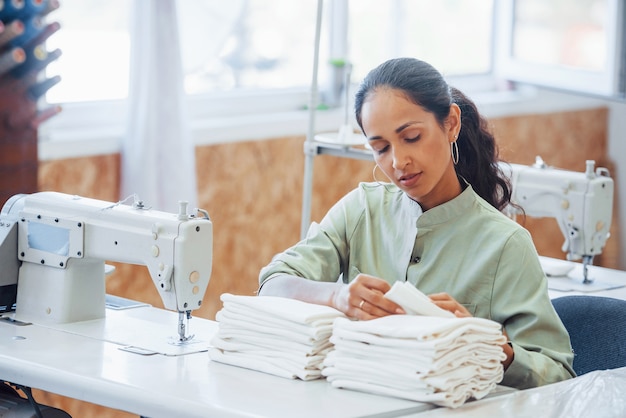 Mujer modista cose ropa en la máquina de coser en la fábrica