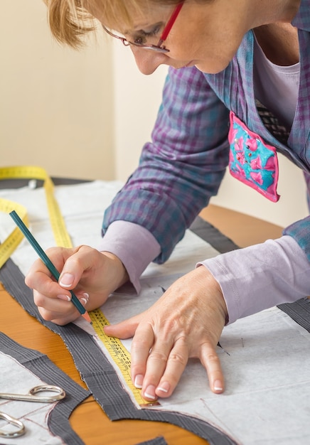 Mujer modista dibujo patrón de sastre con lápiz para un traje en la mesa