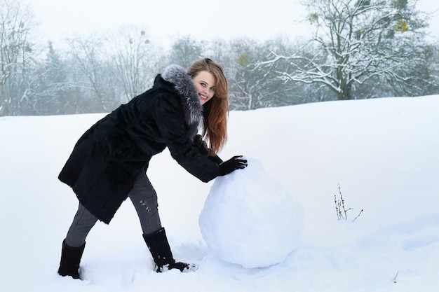 Mujer moldea una gran bola de la nieve.