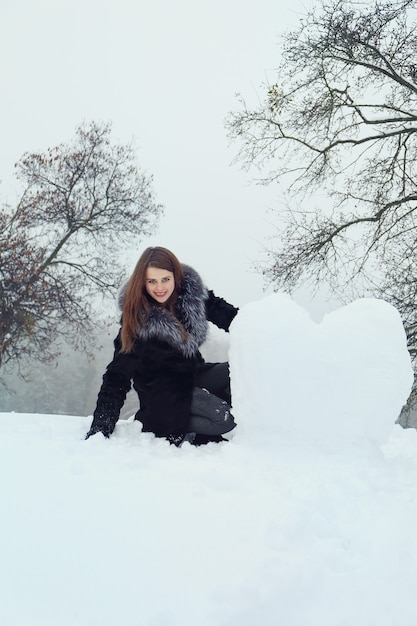 Mujer moldea un gran corazón de la nieve.