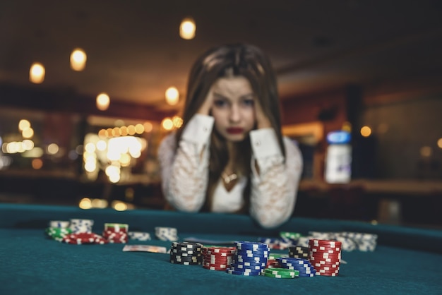 Mujer molesta en casino sentado detrás de la mesa de póquer