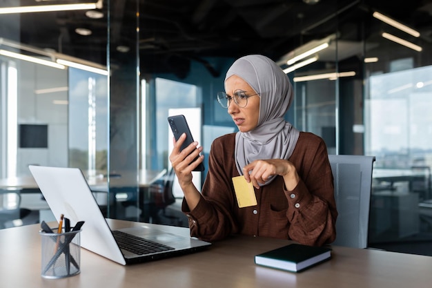 Mujer molesta y decepcionada con hiyab dentro de la oficina tratando de hacer una compra en el negocio de la tienda en línea