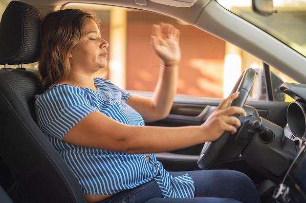 Foto mujer molesta y frustrada mientras conduce a punto de golpear el volante con la mano