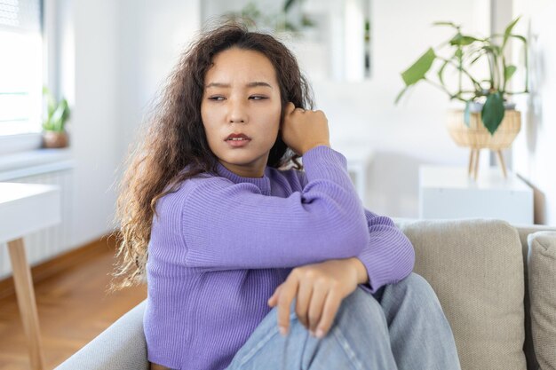 Foto mujer molesta frustrada por problemas con el trabajo o las relaciones sentada en el sofá cubierta cara en mano sintiendo desesperación y ansiedad soledad teniendo problemas psicológicos