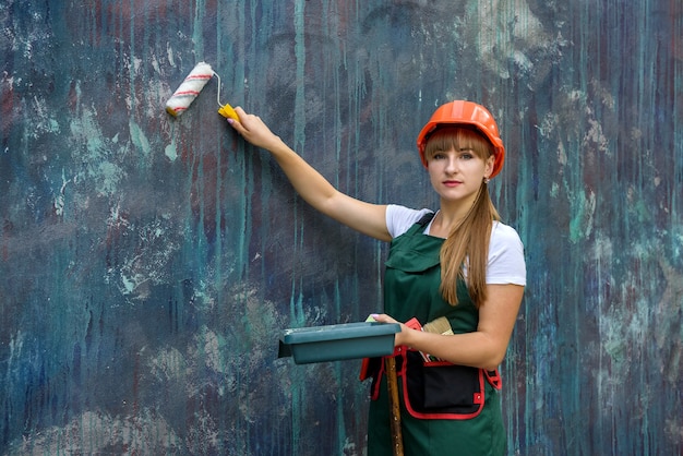 Mujer, en, mono, y, casco, pintura, pared, con, rodillo