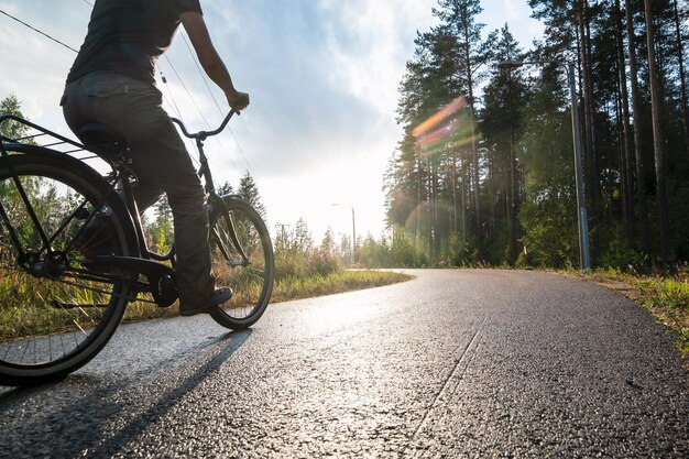 Una mujer monta una bicicleta en un carril bici bajo la lluvia en una tarde bajo el sol