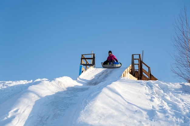 La mujer monta un tubo desde un tobogán en invierno en una nevada Tubo deportivo de invierno al aire libre Enfoque selectivo