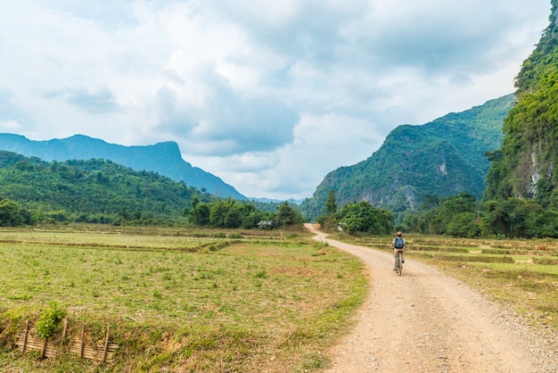 Mujer montando bicicleta de montaña en camino de tierra en paisaje escénico