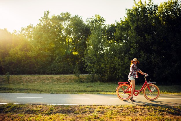 Mujer montando en bicicleta vintage en el parque de verano