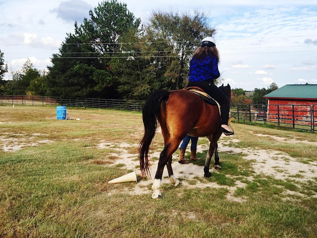 Foto mujer montando a caballo en un rancho