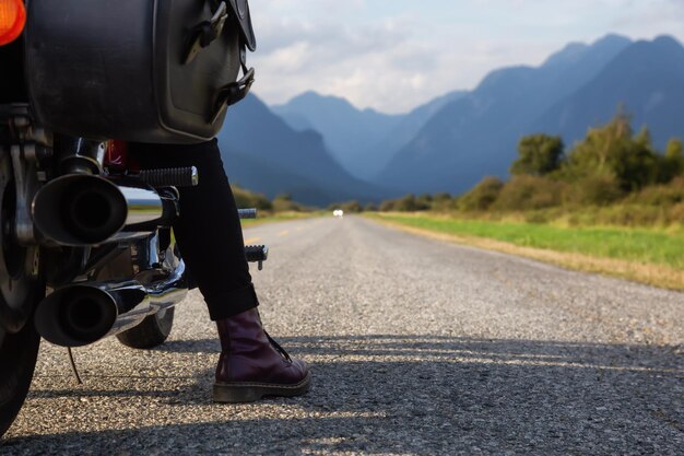 Mujer montando una motocicleta en una pintoresca carretera rodeada de montañas canadienses