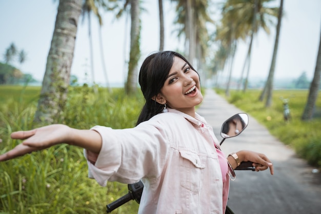 Mujer montando su bicicleta scooter en carretera tropical