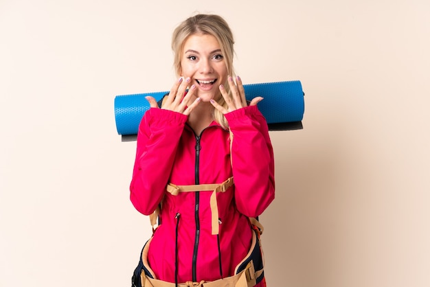 Mujer montañista con una mochila grande aislada con expresión facial sorpresa