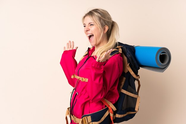 Mujer montañista con una mochila grande sobre pared aislada con expresión facial sorpresa