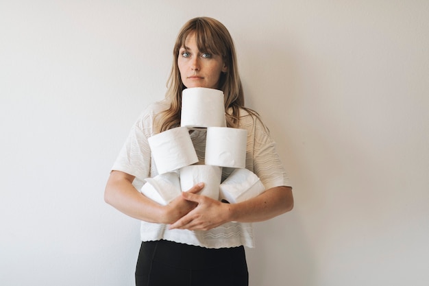 Foto mujer con un montón de rollos de papel higiénico