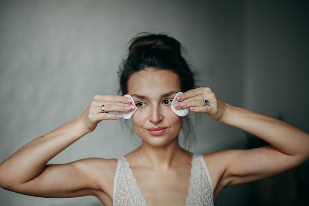 Foto mujer morena de 30 años se quita el maquillaje con bastoncillos de algodón