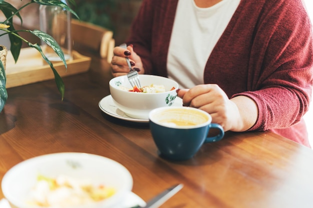 Mujer morena adulta con gafas en ropa casual de talla grande cuerpo positivo almorzando