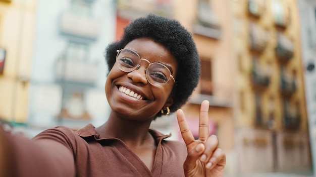 Mujer morena afroamericana positiva tomando selfie en str