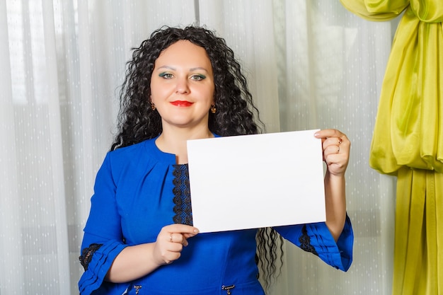 Mujer morena alegre rizada sosteniendo una placa de espacio de copia en sus manos. Foto horizontal