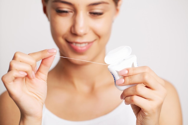 Mujer morena alegre usando hilo dental en el baño.